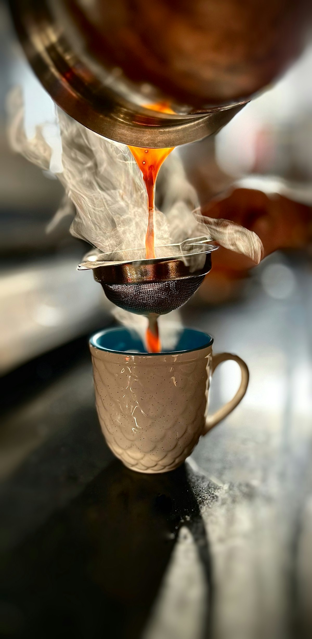 Chai poured through a strainer into a cup