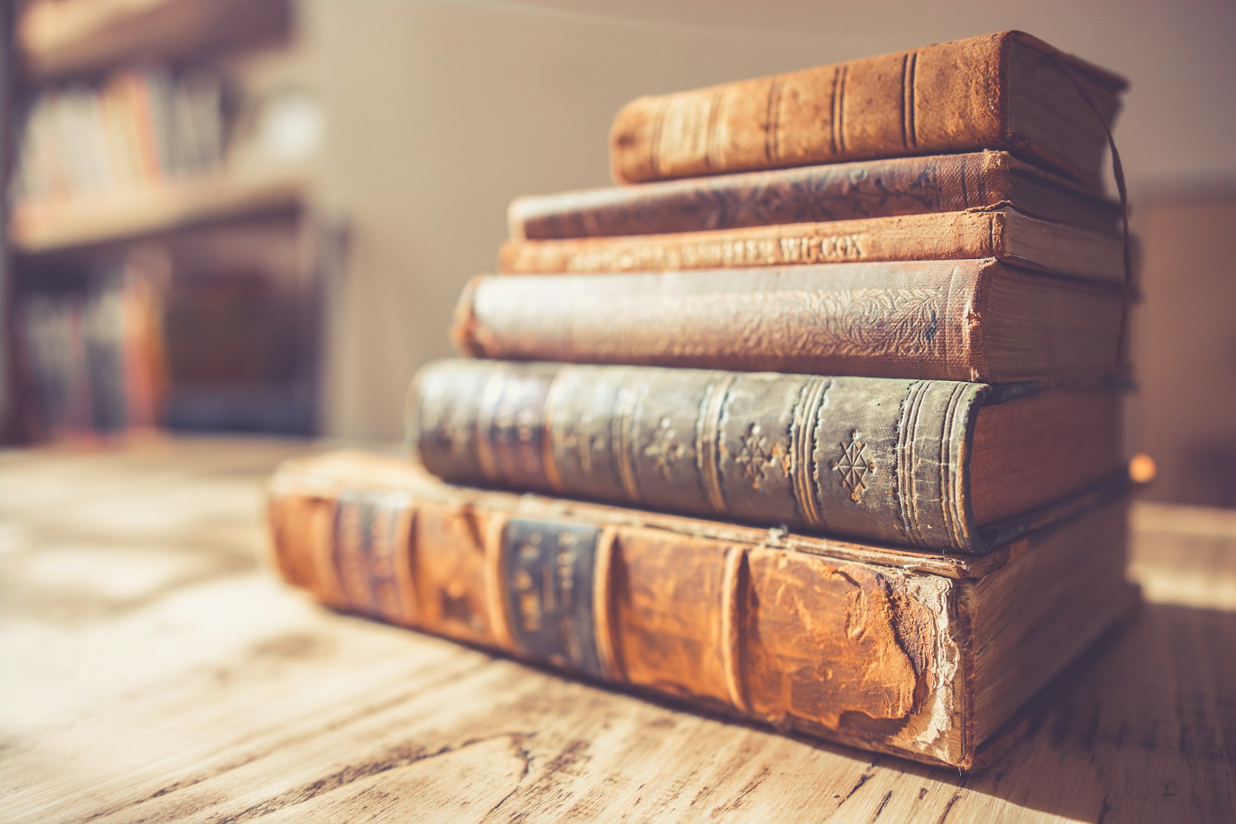 A stack of well loved antique books on a wooden table