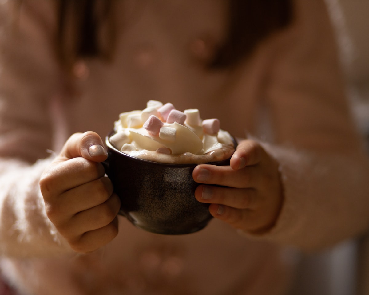 Hands holding a mug of hot chocolate with marshmallows