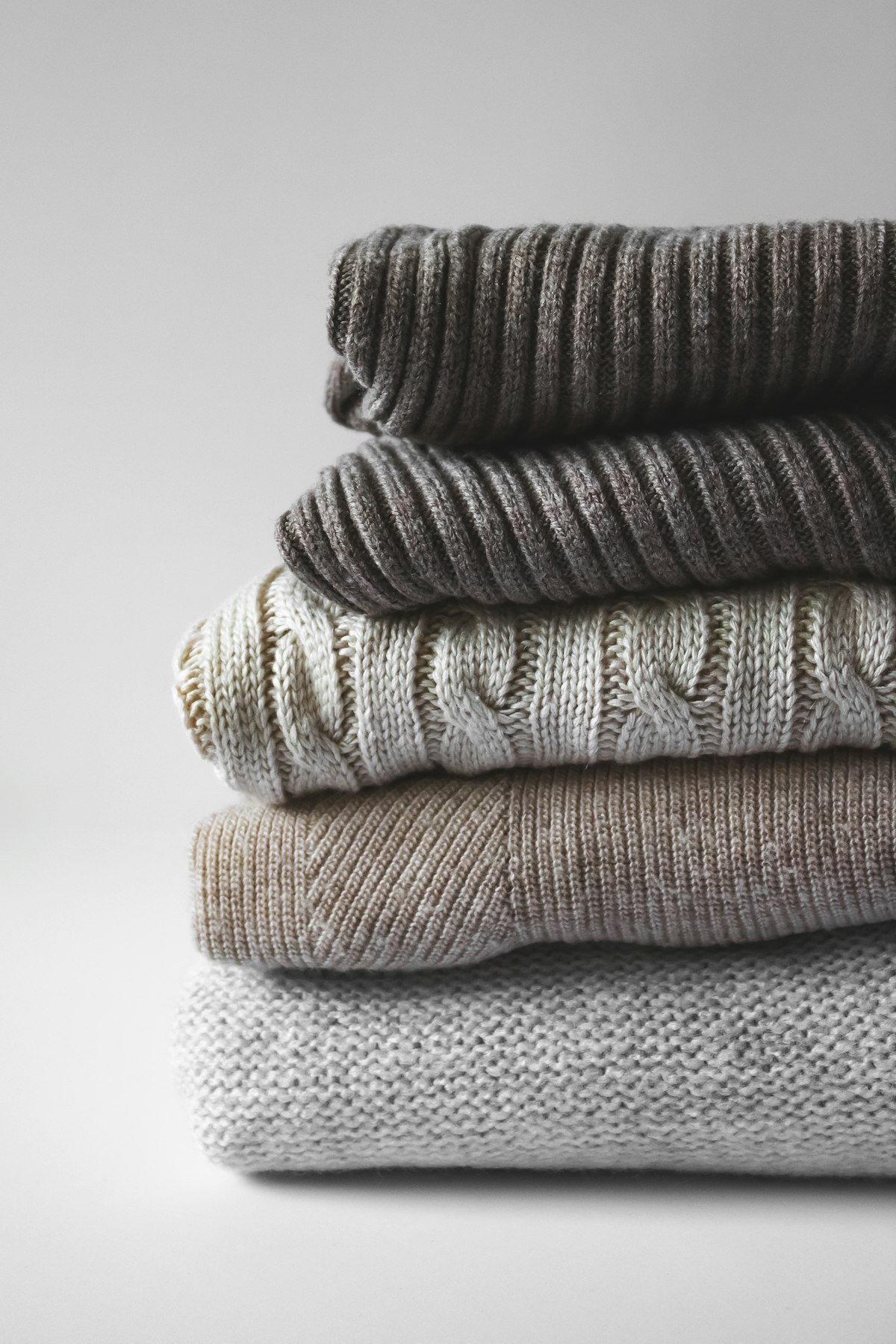 Stack of folded neutral knit sweaters