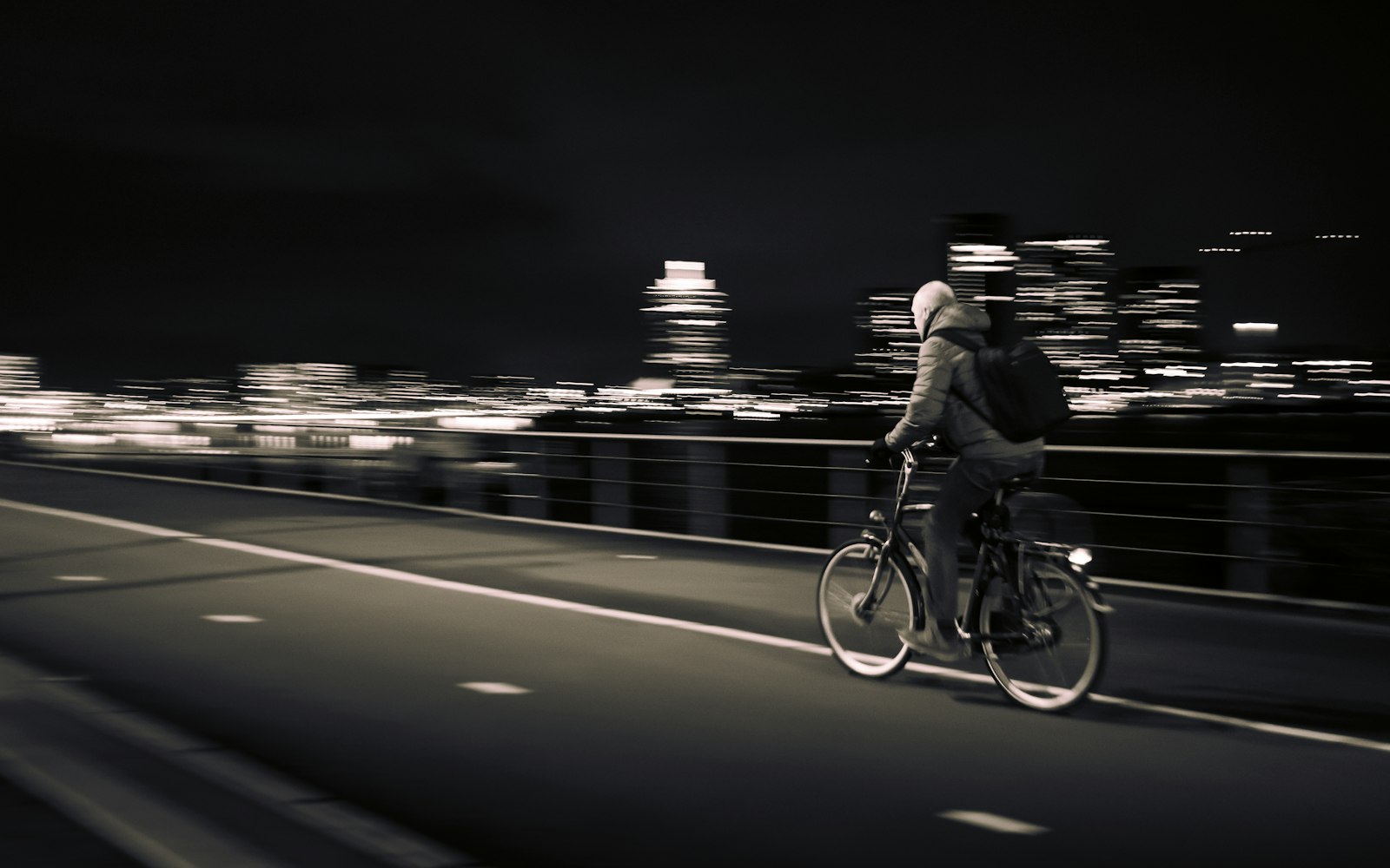 Commuter riding across a bridge at night with the city behind